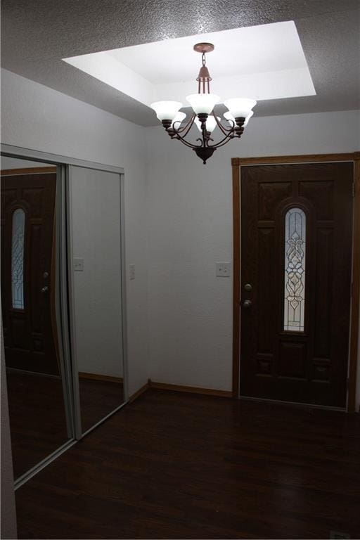 entrance foyer with dark hardwood / wood-style floors, a textured ceiling, a chandelier, and a tray ceiling