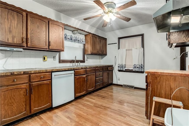 kitchen featuring dishwasher, a textured ceiling, a sink, and light wood-style floors