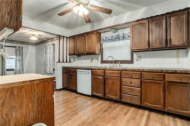 kitchen with ceiling fan, a textured ceiling, a sink, light wood-style floors, and dishwasher