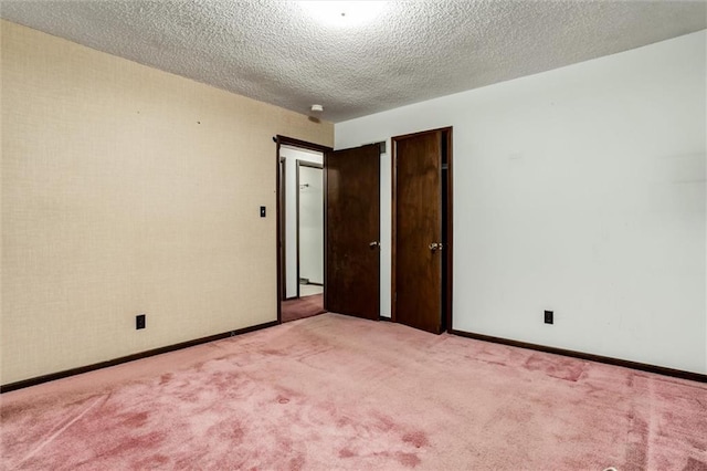 unfurnished room featuring a textured ceiling, baseboards, and light colored carpet