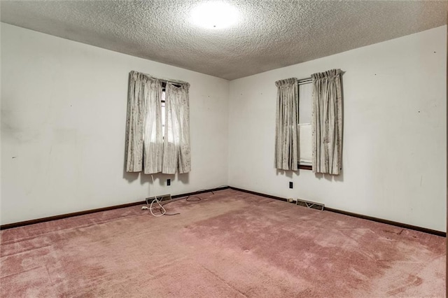 carpeted empty room featuring baseboards, visible vents, and a textured ceiling