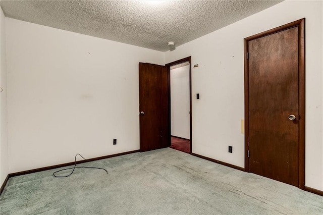 carpeted empty room featuring a textured ceiling and baseboards