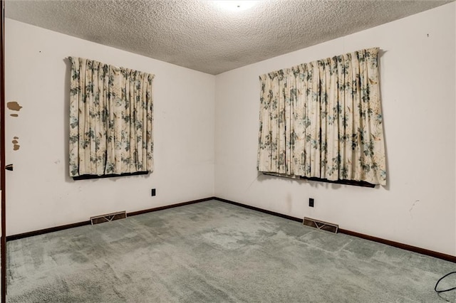 unfurnished room with baseboards, visible vents, a textured ceiling, and carpet flooring