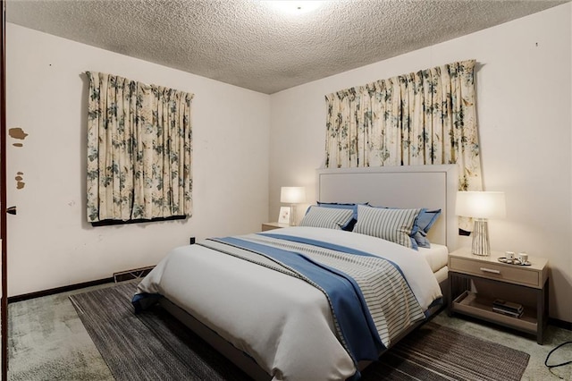 bedroom with a textured ceiling, carpet floors, visible vents, and baseboards