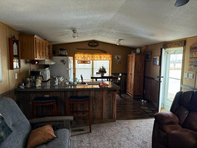 137 Halls Dr, Craig, MO 64437 - kitchen featuring vaulted ceiling, sink, white fridge, kitchen peninsula, and a textured ceiling