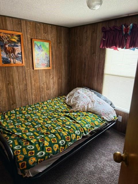 137 Halls Dr, Craig, MO 64437 - bedroom with wooden walls, a textured ceiling, and carpet