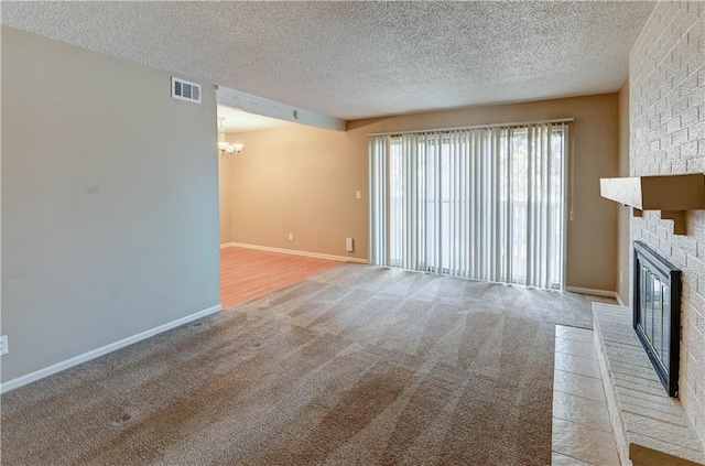 unfurnished living room with an inviting chandelier, a fireplace, light carpet, and a textured ceiling