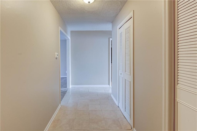 hallway featuring light tile patterned floors and a textured ceiling