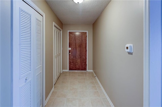 hall featuring light tile patterned floors and a textured ceiling