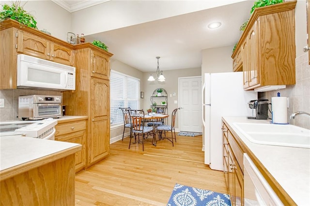 kitchen featuring decorative light fixtures, sink, backsplash, white appliances, and light hardwood / wood-style flooring