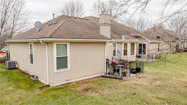 back of house with central AC unit and a lawn