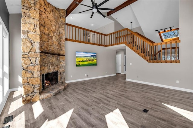 unfurnished living room featuring a fireplace, visible vents, ceiling fan, wood finished floors, and baseboards