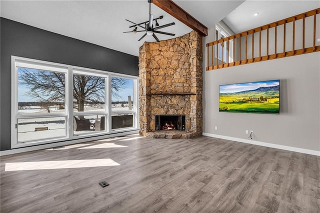 unfurnished living room with beam ceiling, baseboards, and wood finished floors