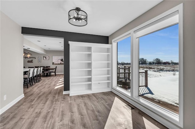 interior space featuring light wood finished floors, baseboards, visible vents, and a chandelier