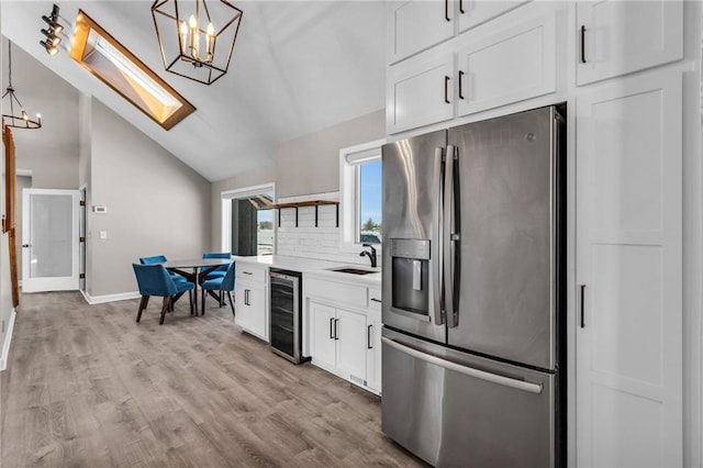 kitchen featuring beverage cooler, decorative light fixtures, stainless steel fridge with ice dispenser, and white cabinetry