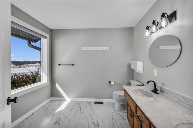 half bath with toilet, marble finish floor, baseboards, and vanity