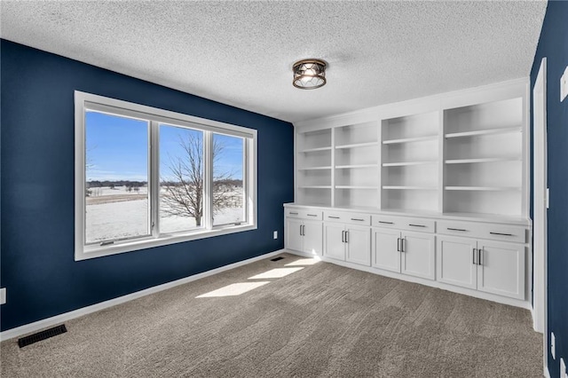 empty room featuring visible vents, light carpet, baseboards, and a textured ceiling