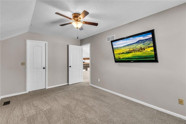 unfurnished bedroom with light colored carpet, visible vents, a textured ceiling, and baseboards