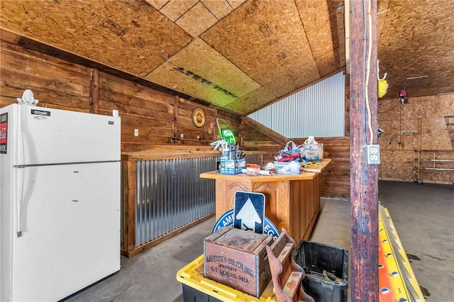 miscellaneous room featuring vaulted ceiling, wood walls, and concrete flooring