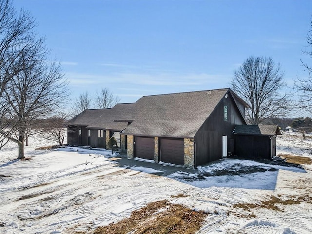 view of front facade featuring an attached garage, stone siding, and a shingled roof