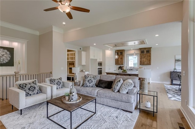 living room featuring crown molding, ceiling fan, and light wood-type flooring