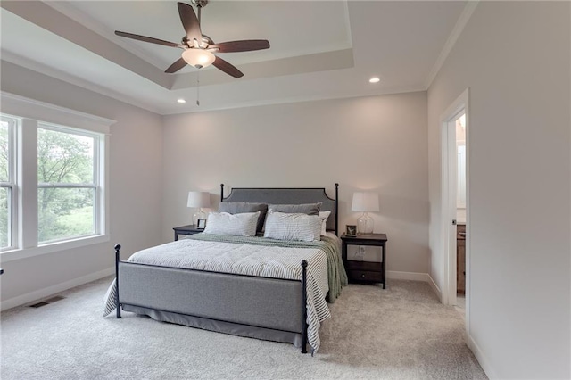 bedroom with crown molding, ceiling fan, a tray ceiling, and light carpet