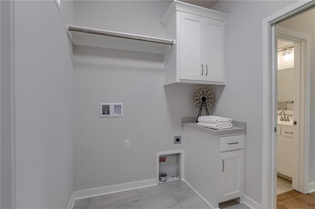 laundry area featuring baseboards, hookup for a washing machine, cabinet space, hookup for an electric dryer, and a sink