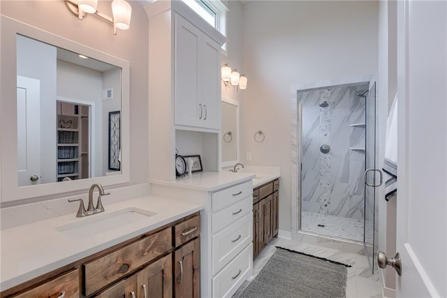 full bath with visible vents, a marble finish shower, two vanities, a sink, and marble finish floor