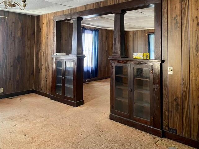 interior space with dark brown cabinets, light colored carpet, and wooden walls