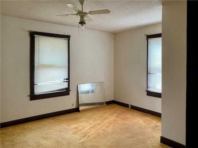 empty room featuring light carpet, ceiling fan, and a textured ceiling