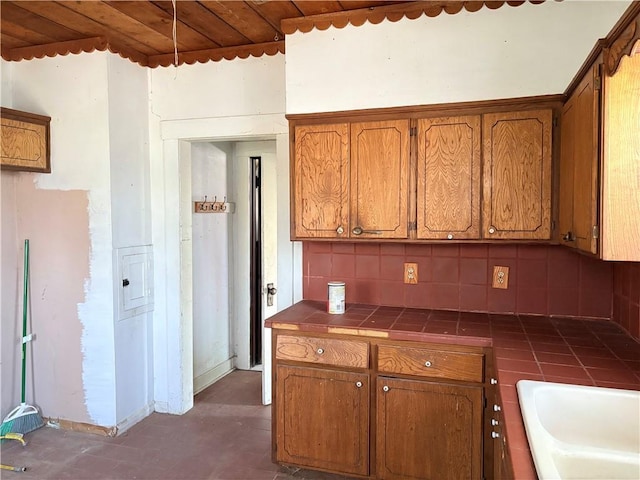 305 E 8th St, Wellsville, KS 66092 - kitchen with brown cabinetry, a sink, tile counters, and backsplash