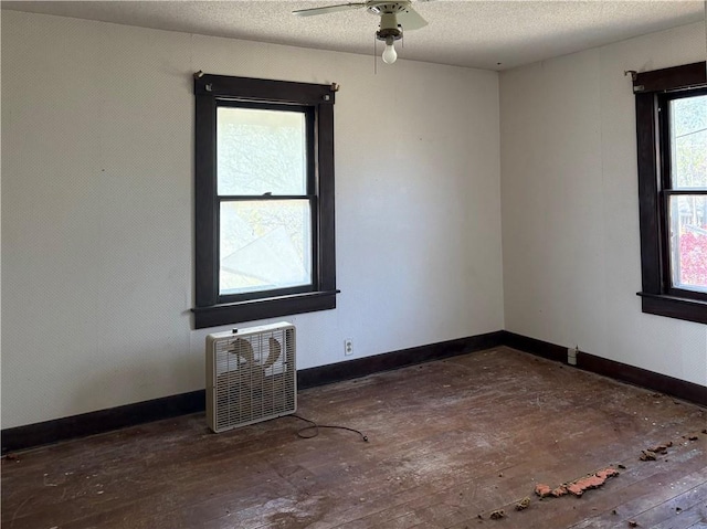 305 E 8th St, Wellsville, KS 66092 - unfurnished room featuring baseboards, hardwood / wood-style floors, heating unit, and ceiling fan