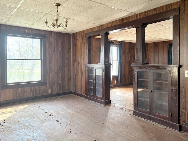 305 E 8th St, Wellsville, KS 66092 - unfurnished room featuring wooden walls, wood-type flooring, a paneled ceiling, and an inviting chandelier