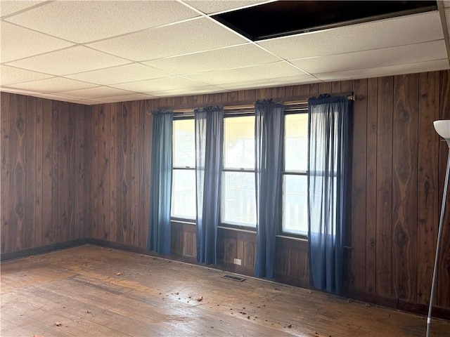 305 E 8th St, Wellsville, KS 66092 - unfurnished room with a paneled ceiling, wood walls, visible vents, and hardwood / wood-style flooring