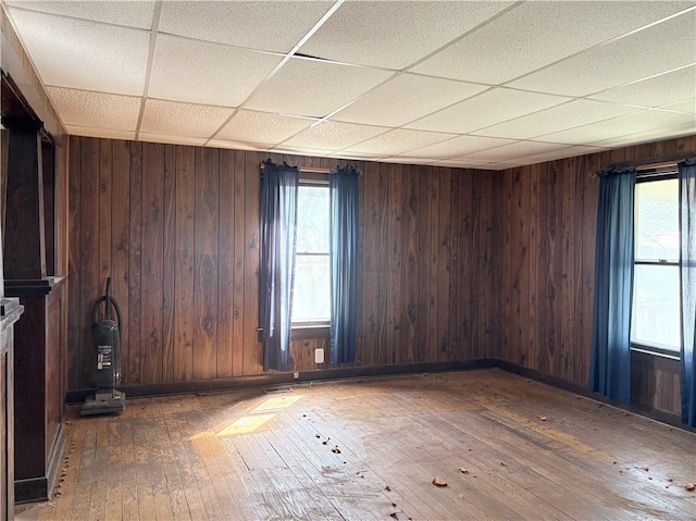305 E 8th St, Wellsville, KS 66092 - unfurnished room with wooden walls, a drop ceiling, hardwood / wood-style flooring, and a healthy amount of sunlight