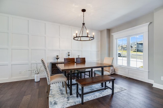 dining area with dark wood-type flooring and a notable chandelier