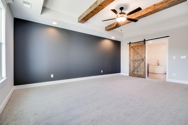 carpeted empty room featuring beam ceiling, a barn door, and ceiling fan