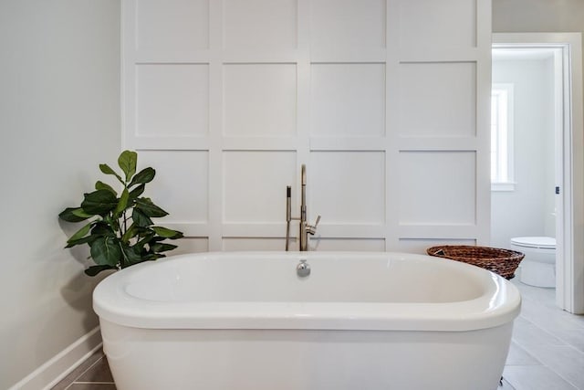 bathroom with tile patterned flooring, toilet, and a tub to relax in