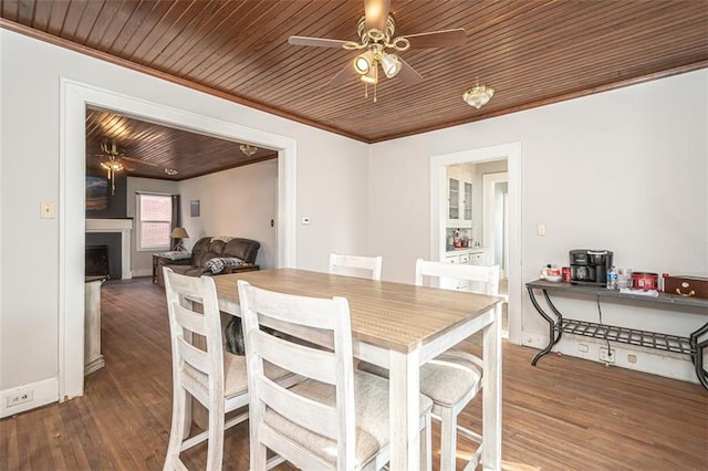 dining space featuring crown molding, dark hardwood / wood-style flooring, wooden ceiling, and ceiling fan