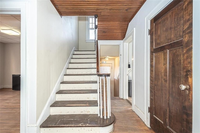 staircase with hardwood / wood-style flooring, a drop ceiling, and wooden ceiling