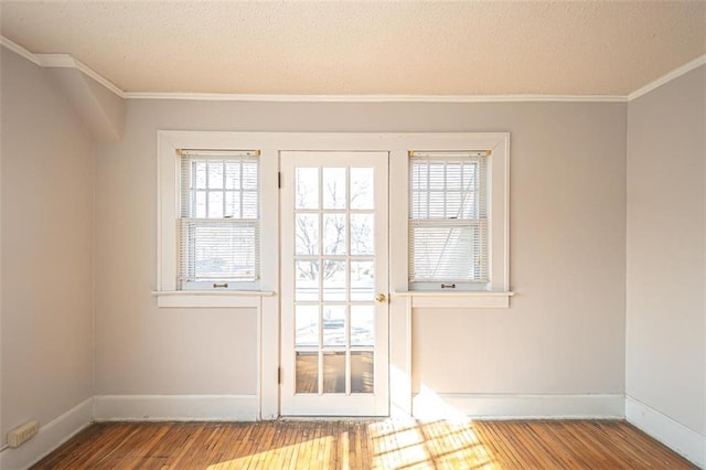 doorway featuring hardwood / wood-style flooring, ornamental molding, and a textured ceiling