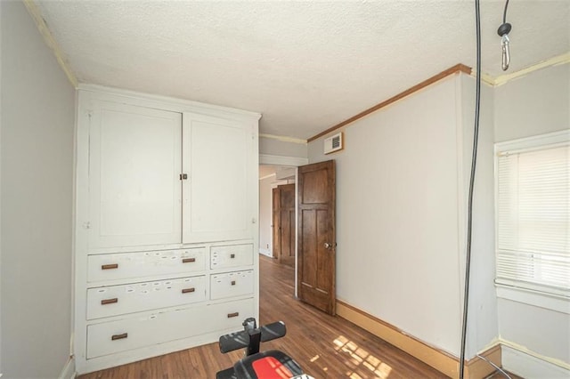 workout room with hardwood / wood-style flooring, ornamental molding, and a textured ceiling