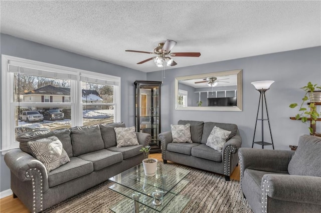 living room with ceiling fan, wood-type flooring, and a textured ceiling