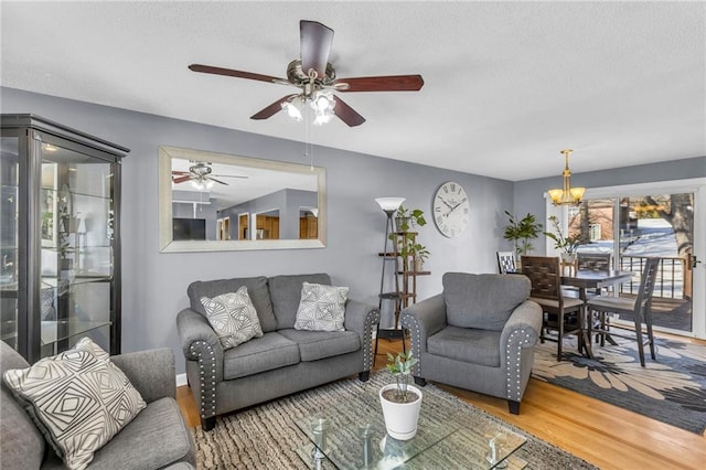 living room with wood-type flooring and ceiling fan with notable chandelier