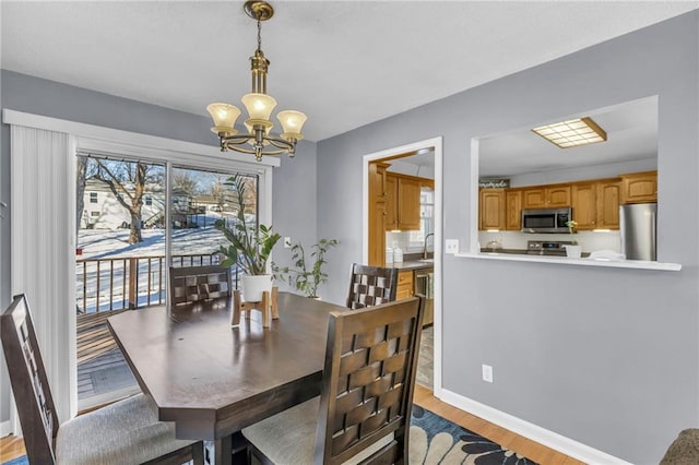 dining area featuring sink, a chandelier, and light wood-type flooring