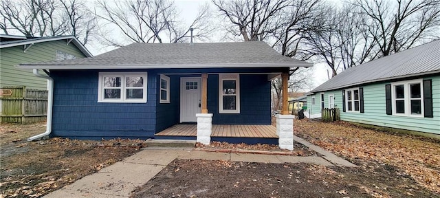 bungalow-style house with a porch, a shingled roof, and fence