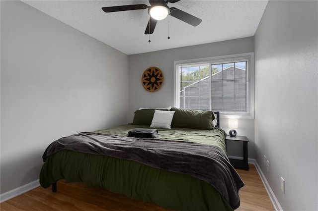 bedroom featuring ceiling fan, a textured ceiling, and light hardwood / wood-style floors