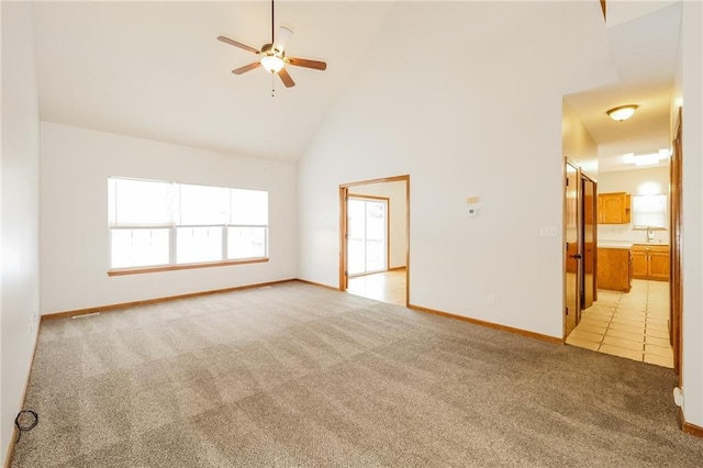 empty room with ceiling fan, light colored carpet, and high vaulted ceiling