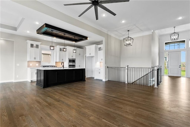 kitchen featuring a kitchen island with sink, white cabinetry, pendant lighting, and stainless steel appliances