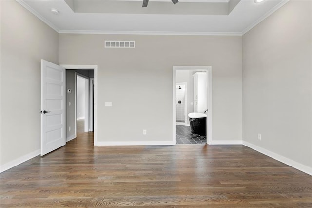 unfurnished bedroom featuring a raised ceiling, ensuite bathroom, ornamental molding, and dark hardwood / wood-style flooring